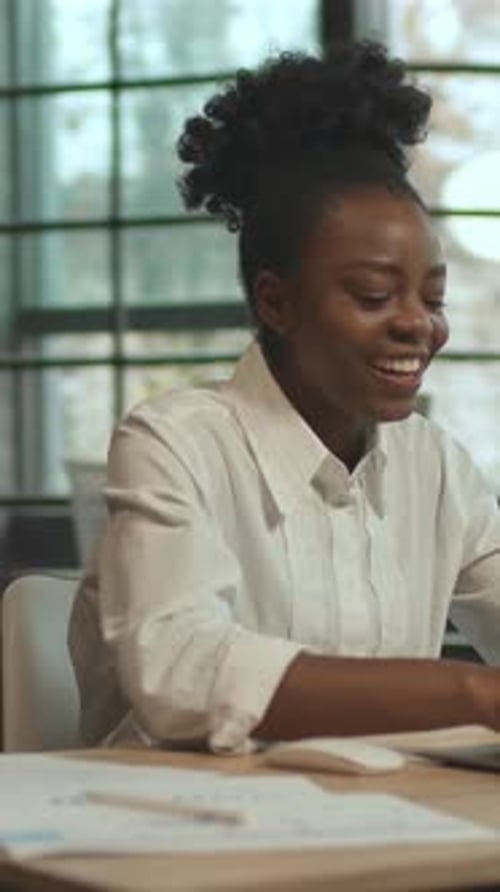 Smiling Woman Using Laptop at Desk in Modern Office