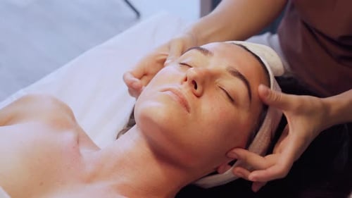 Woman getting facial massage in spa salon