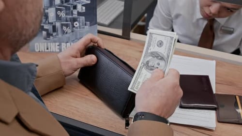 Unrecognizable Man Exchanging Dollar Bills with Bank Employee
