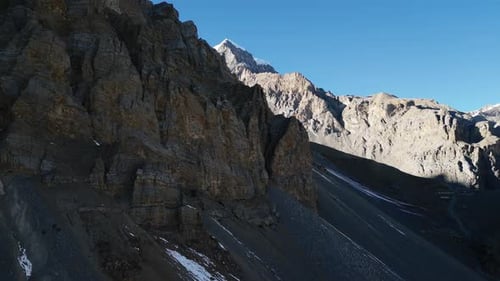 Flying over rocky stone formations, steep mountain ranges and blue sky in Nepal