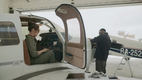 Female Aviation Inspector Using Laptop and Checking on Technician in Hangar
