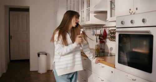 Carefree Woman Dancing and Singing in Kitchen