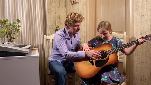 Young Girl Learning Guitar with an Instructor Indoors