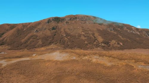 Colorful autumn vegetation in a mountainous area. Clip. A sunny day, blue sky and golden hills.