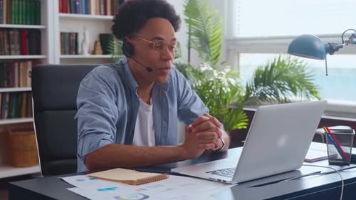 Young African American Man in Call Center Headset in Office Desk with Laptop