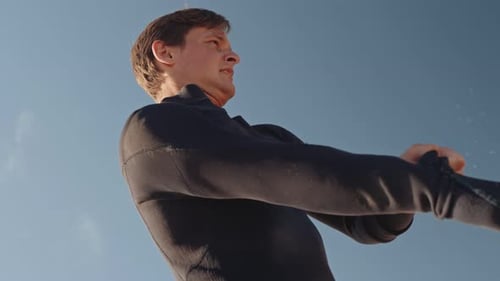 Man in Wetsuit Shaking Sand from Arms