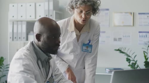 Diverse Doctors Discussing Medical Test Results on Laptop in Clinic