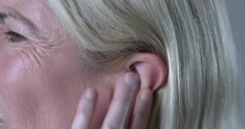 Woman suffering tinnitus, rubbing ringing ear