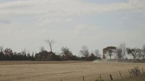 Dust From A Combine Harvester Tractor On Wheat Crops At The Field. Wide Shot