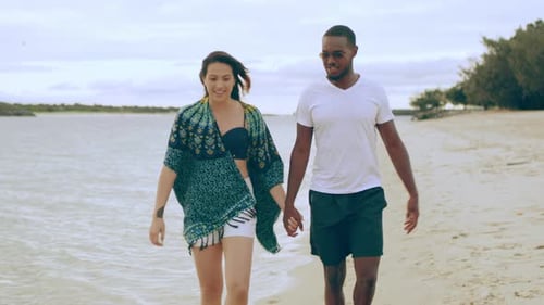 Young couple holding hands enjoying a romantic walk on an australian beach
