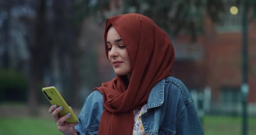 Young Woman Smiles in Scarf with Smartphone