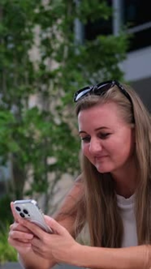 Young Woman Using Smartphone Outdoors in Modern Business District