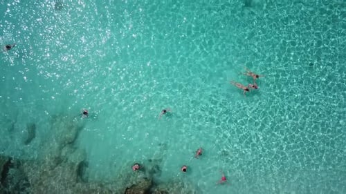 Top down drown shot of Comino Island, blue lagoon, Malta. Tourists enjoying themselves on a rocky cl