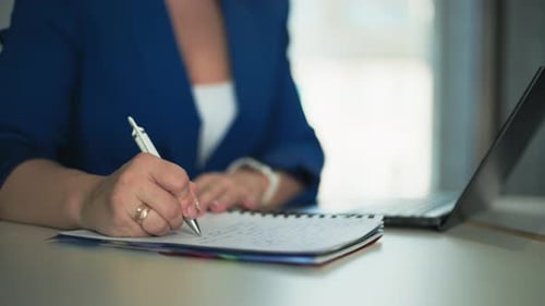 Woman's Hands Writing Notes Near Laptop