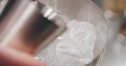 Macro de um barman profissional está preparando um coquetel alcoólico com cubo de gelo em uma coqueteleira para