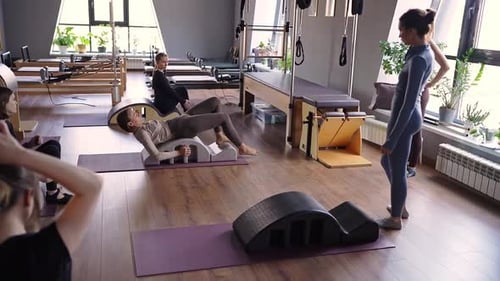 Group of Women Doing Exercises on Back Spine Corrector Reformer Pilates Studio Machine for Fitness