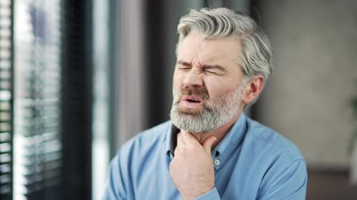 Adult Male Gripping Sore Throat in Interior Setting