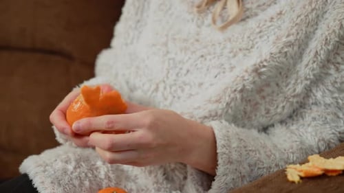 Hands Peeling Orange with Textured Clothing in Background Fingers Carefully Removing Citrus Peel