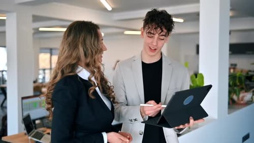 Business session in an office. Woman and a young man discussing business affairs, tablet. Slow motio