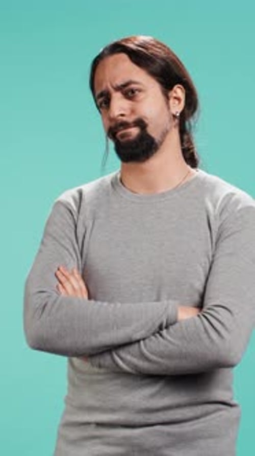 Man Poses with Arms Crossed on Teal Backdrop