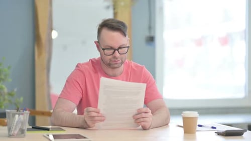 Man Reading Documents at a Modern Office Desk