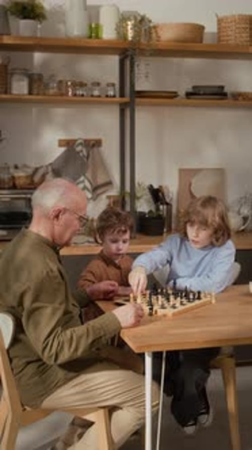Senior Grandfather Playing Chess with Little Grandsons at Home