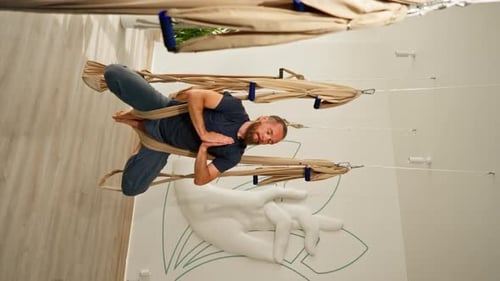 Man Doing Aerial Yoga Hammock Pose in Studio