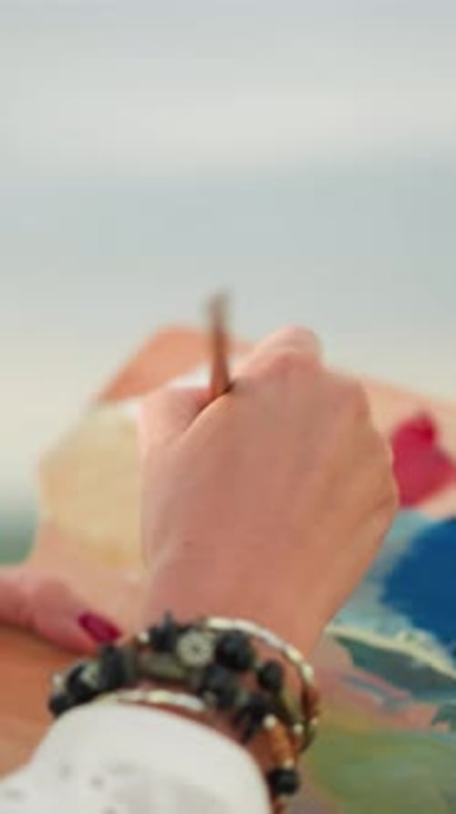 Artist Hand Painting on Canvas by the Ocean