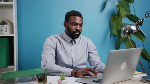 A Professional Man Engaged in Work on His Laptop Within a Modern Stylish Office Space