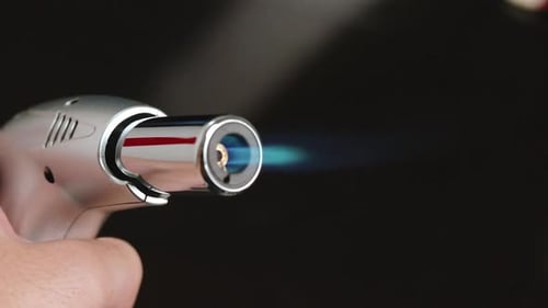Male Hand Holding and Using Blow Torch in Front of Camera on a Dark Background, Close-up on Tip