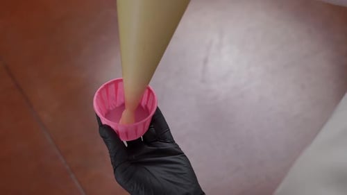 Top View Closeup Pouring Muffin Dough From Pastry Bag in Pink Form Indoors