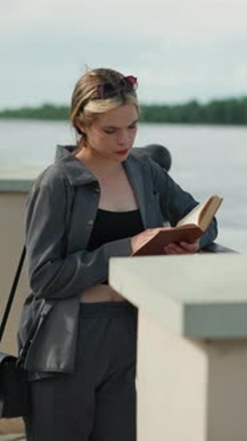 Woman Reading Book on City Ledge