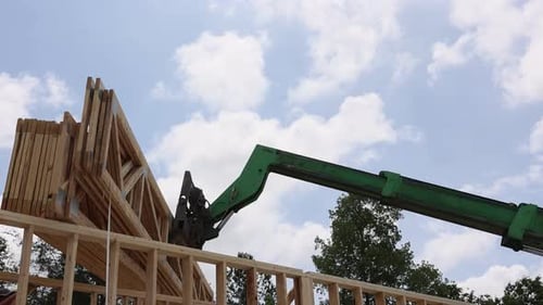 Construction Equipment Lifts Wooden Trusses Beams at Residential Building Site