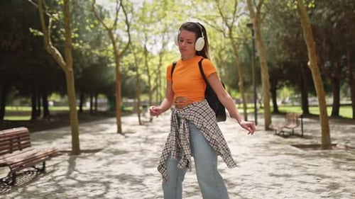 Young Woman Dancing with Headphones in the Park