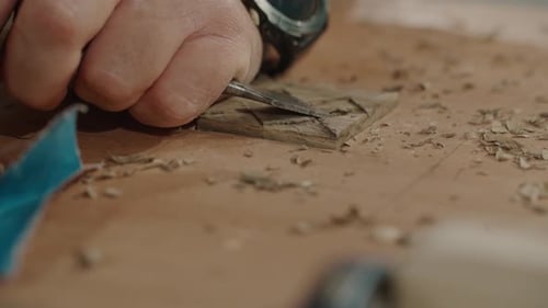 Man Carving Wood with Chisel in a Workshop