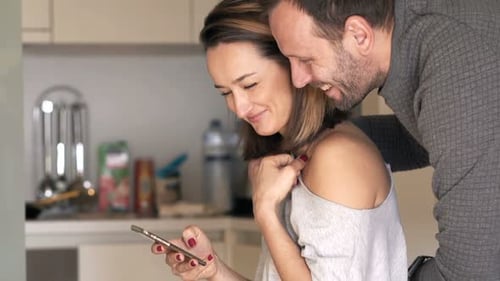 Couple Looking at Phone Together in Kitchen