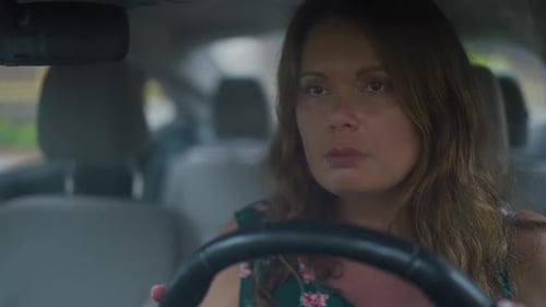 Retrato de uma mulher triste de tamanho grande sentada no banco do motorista no volante com limpadores de carro passando