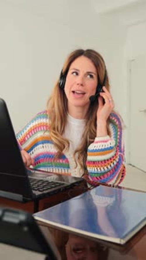 Woman with Headset Working on Laptop at Desk