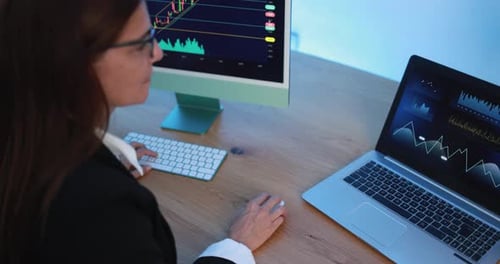 Woman Analyzing Financial Data on Computer and Laptop
