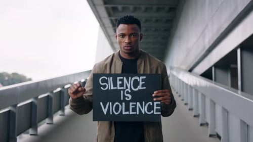 Young Man Holding Protest Sign on Urban Bridge
