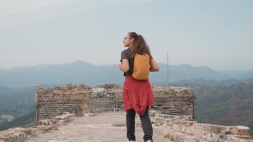 Viajante em pé em um penhasco histórico com vista para montanhas Mulher aventureira faz uma pausa em Arcaico