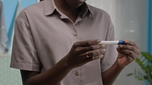 Woman Holding Pregnancy Test Smiling in Bathroom