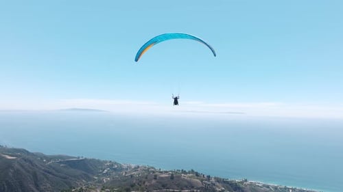 Extremer Gleitschirm fliegt bei klarem blauem Himmel in Richtung Filmmusik Pazifik