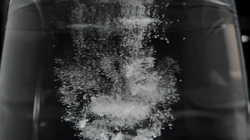 Close-up of Creatine powder dissolving in water, forming clumps as ...