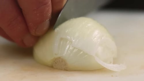 Chef's Hands Slicing Fresh Onion on Cutting Board