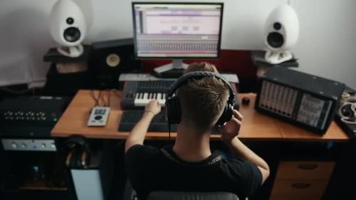 Young sound engineer listening to the music in headphones in the professional studio