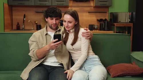 Couple Looking at Smartphone on Sofa at Home