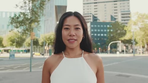 Close up of beautiful smiling young woman looking at camera on modern city background