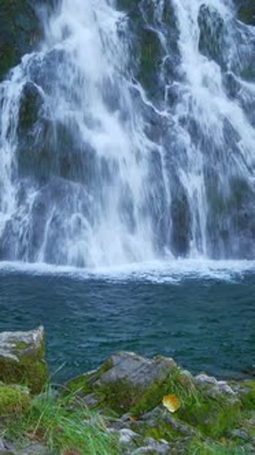 Une cascade majestueuse se jette dans une piscine sereine entourée d'un environnement verdoyant