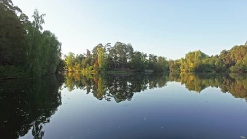 Flying Over the Surface of the Lake in the Autumn Forest Above